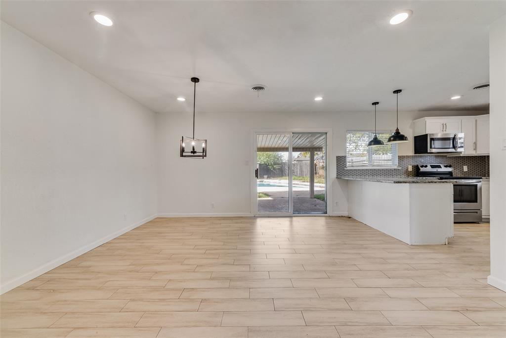 413 Simmons Drive Hurst, TX 76053 - Photo 23 of 26 a view of kitchen with stainless steel appliances granite countertop a stove top oven a sink dishwasher a refrigerator and white cabinets with wooden floor