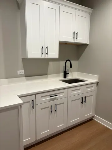 a kitchen with stainless steel appliances granite countertop a sink white cabinets and a wooden floor