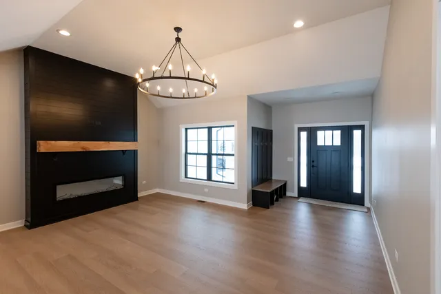 a view of an empty room with wooden floor fireplace and a window