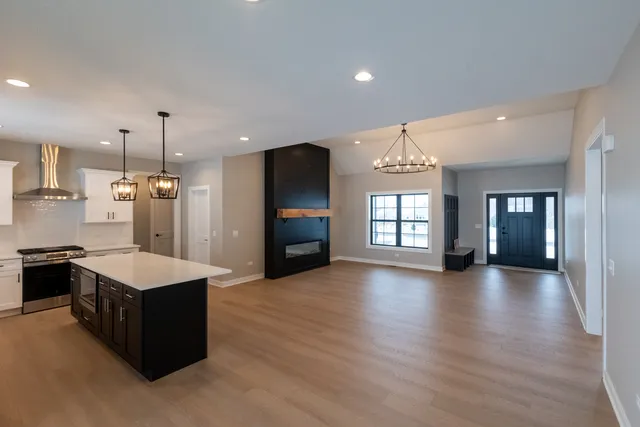 a large kitchen with kitchen island a stove a sink a refrigerator and a dining table with wooden floor