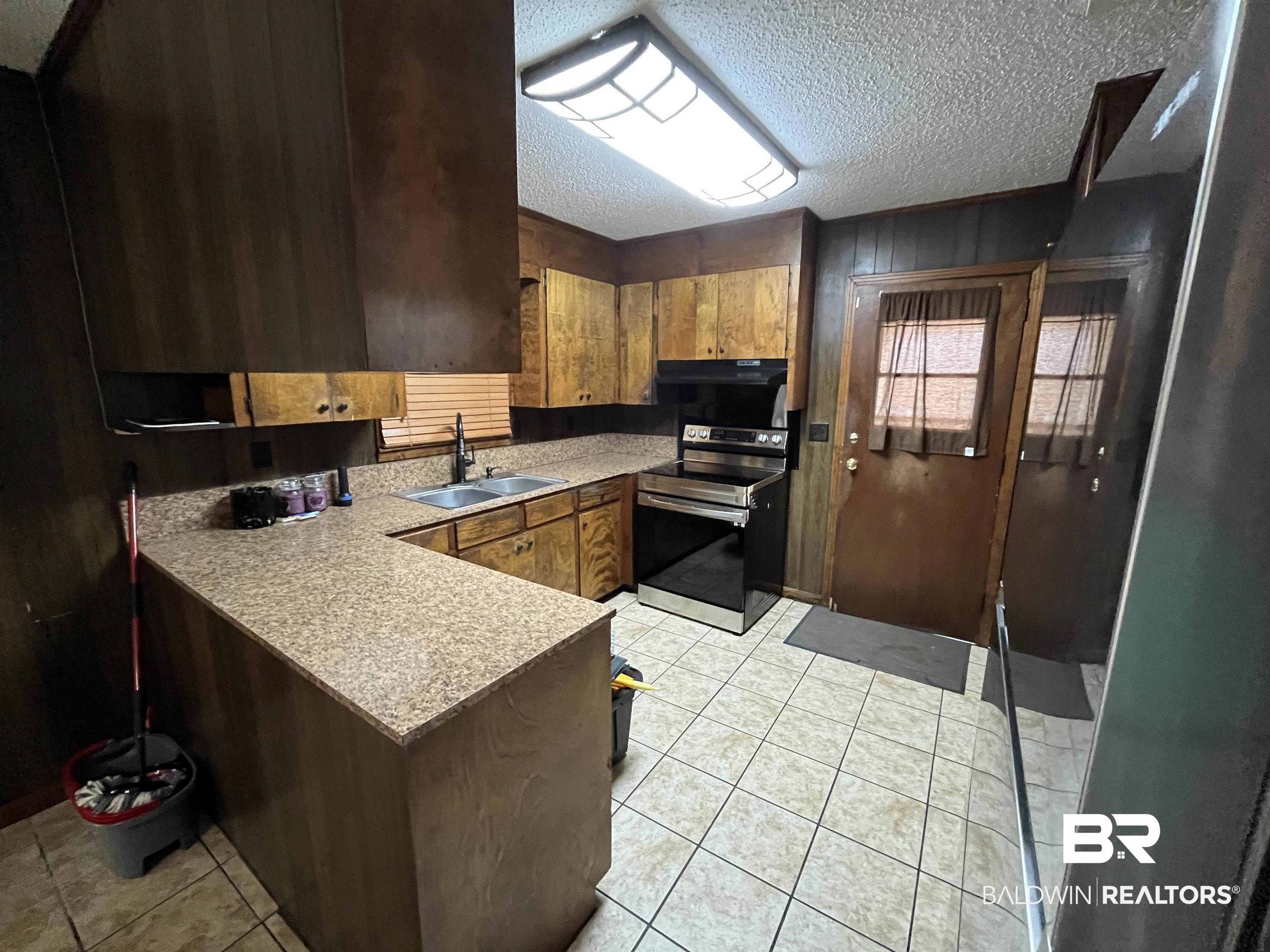 1905 Rockaway Creek Road Atmore, AL 36502 - Photo 11 of 23 Kitchen featuring wood-finish cabinetry, granite-style countertops, and a dual-basin stainless steel sink with a matte black faucet