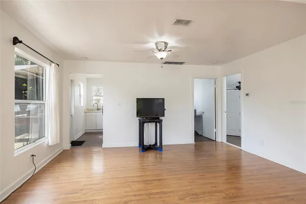 a view of empty room with wooden floor and fan
