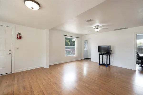 an empty room with wooden floor and windows