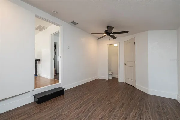 an empty room with wooden floor and a ceiling fan