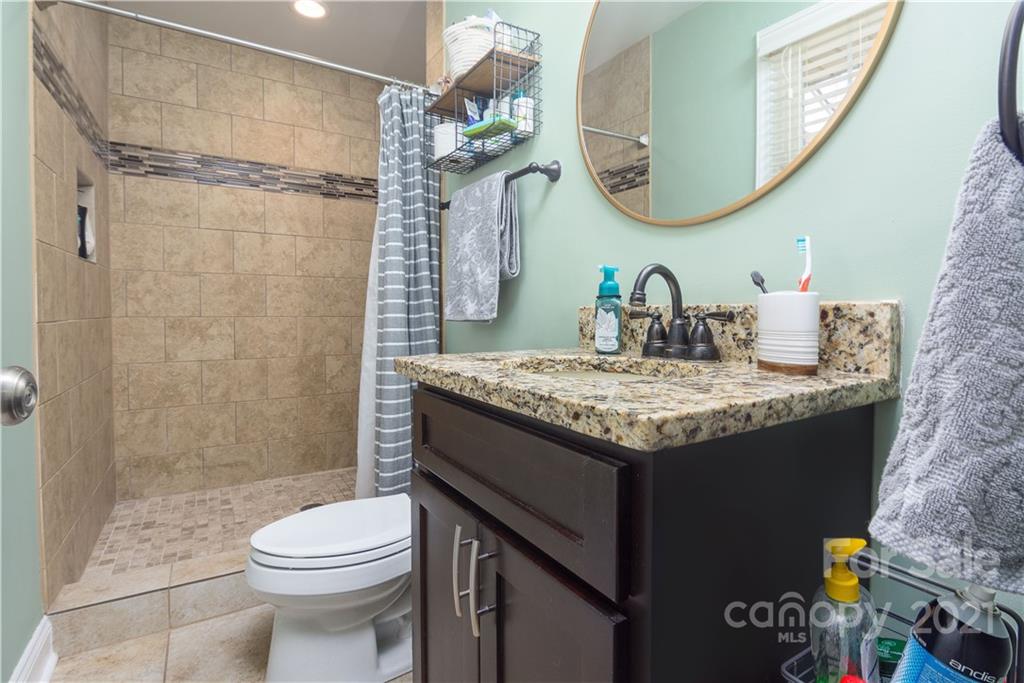 5201 Londonderry Road Charlotte, NC 28210 - Photo 29 of 42 a bathroom with a granite countertop sink a toilet and a mirror