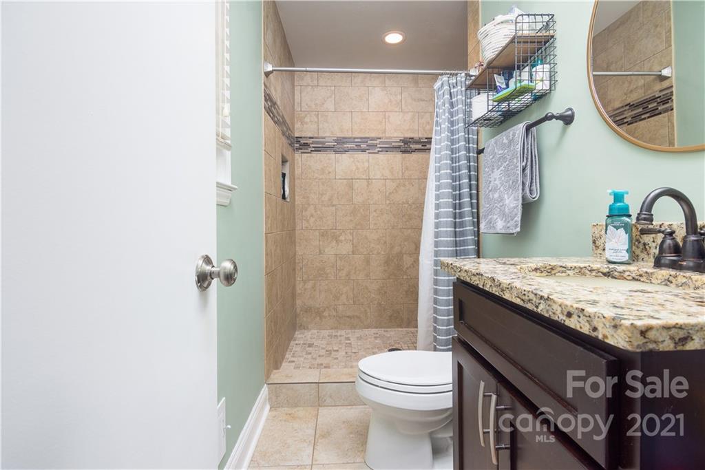 5201 Londonderry Road Charlotte, NC 28210 - Photo 30 of 42 a bathroom with a granite countertop sink a toilet and a shower