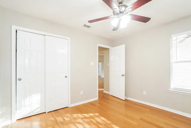 an empty room with windows and fan