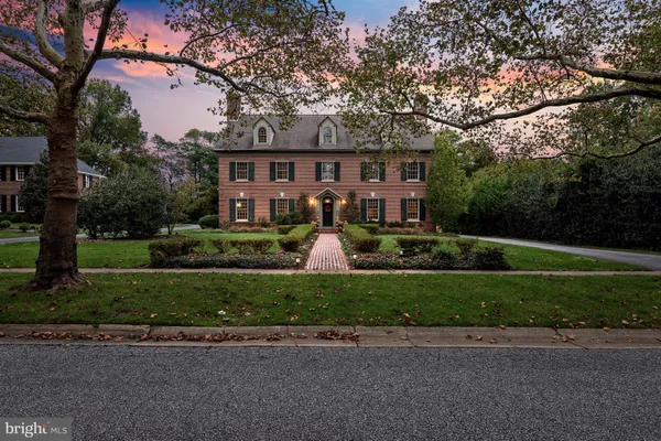 a front view of a house with a garden and trees