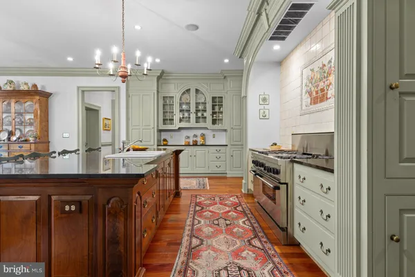 a kitchen with granite countertop a stove a sink a dining table and chairs