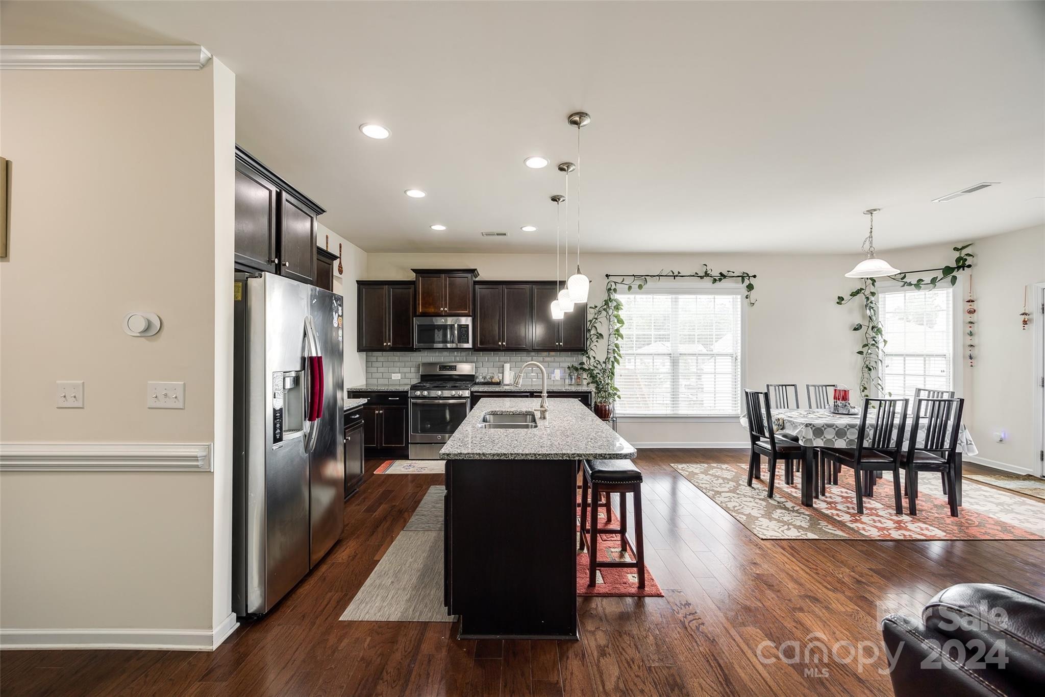 819 Bridge View Court Fort Mill, SC 29708 - Photo 7 of 40 a kitchen with stainless steel appliances granite countertop a stove top oven a refrigerator a dining table and chairs with wooden floor