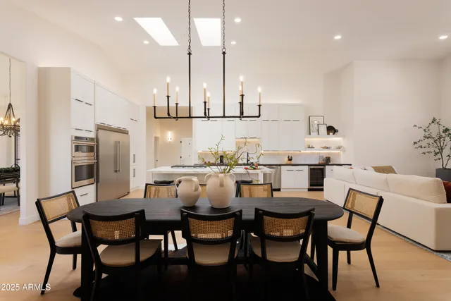 a dining room with stainless steel appliances kitchen island a table chairs and a refrigerator