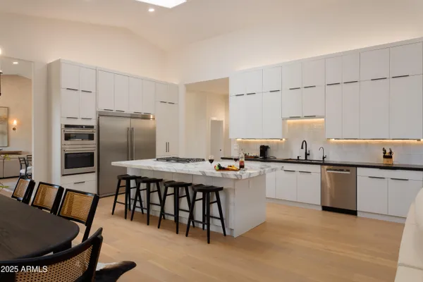 a kitchen with stainless steel appliances granite countertop a stove a sink dishwasher a dining table and chairs