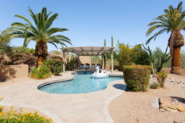 a view of a backyard with swimming pool and chairs