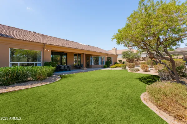 a view of house in front of a big yard with large trees