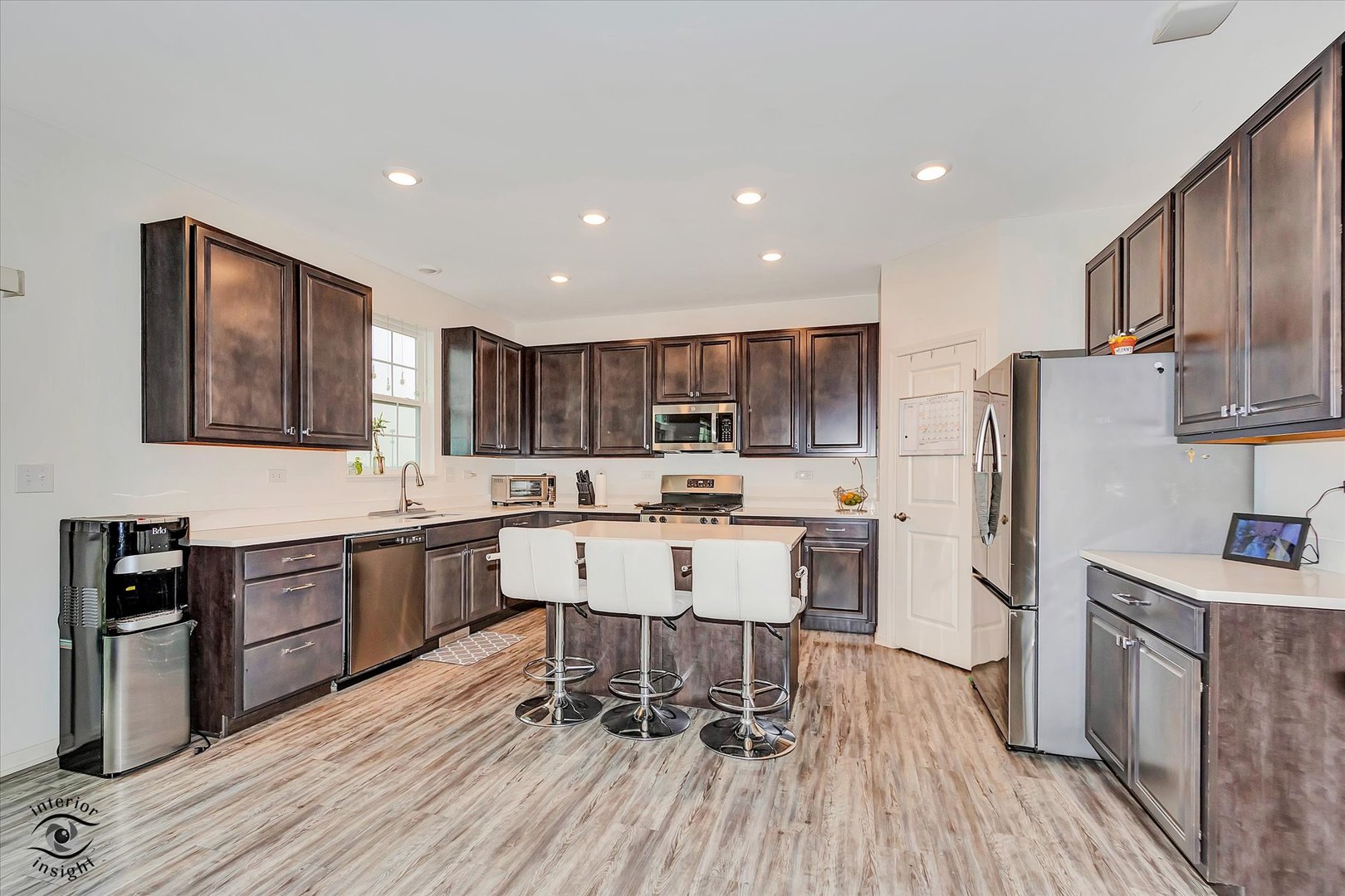 15101 Quincy Way Manhattan, IL 60442 - Photo 8 of 28 a kitchen with stainless steel appliances kitchen island granite countertop a refrigerator a stove a sink a dining table and chairs with wooden floor