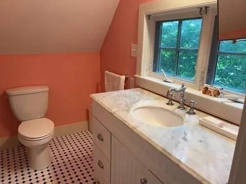 a bathroom with a granite countertop toilet a sink and a window