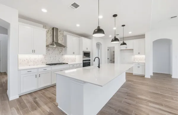 a large white kitchen with a large island oven a sink stainless steel appliances and cabinets