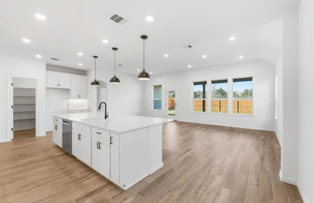 a large kitchen with stainless steel appliances kitchen island a large counter top and a wooden floors