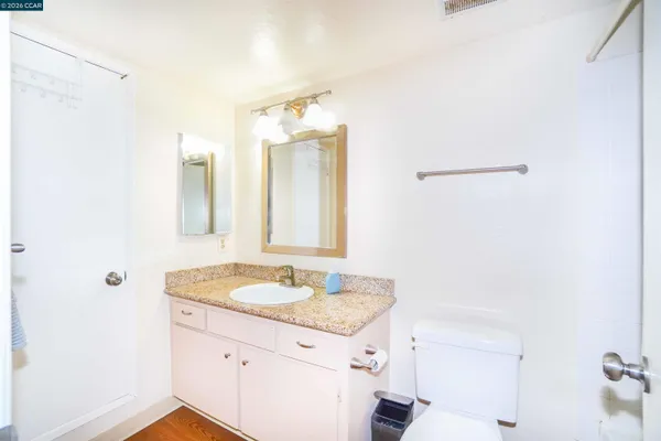 a kitchen with stainless steel appliances granite countertop a refrigerator a sink dishwasher a stove and white countertops with wooden floor