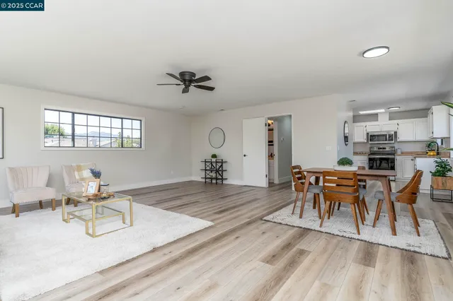 a living room with furniture a dining table and chairs with wooden floor