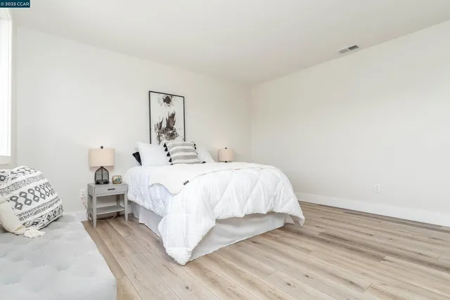 a bed sitting in a spacious bedroom next to a window