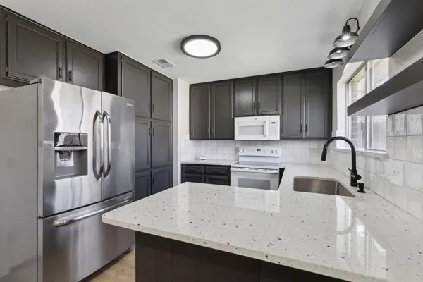 a kitchen with granite countertop a refrigerator and a sink