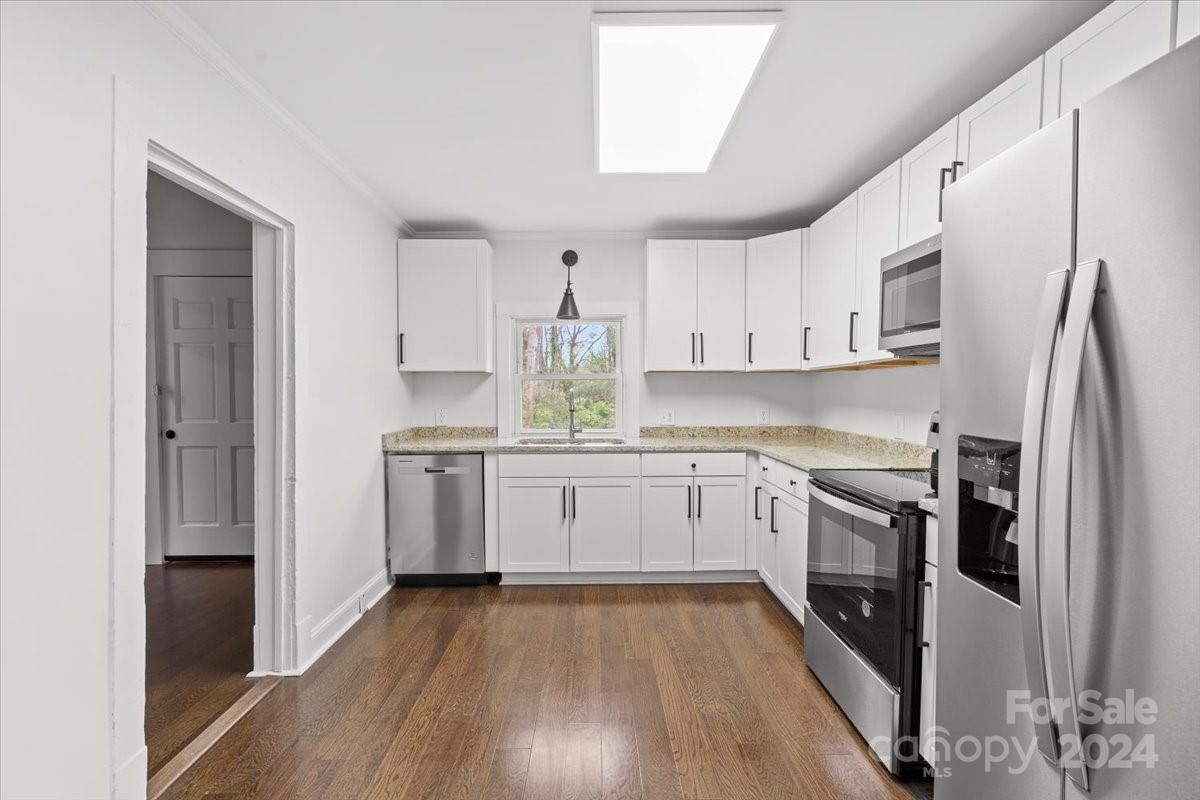 411 West Frederick Street Gaffney, SC 29341 - Photo 8 of 17 a kitchen with white cabinets stainless steel appliances and wooden floor