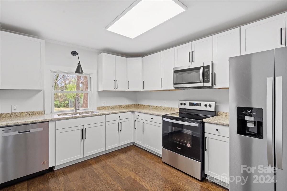 411 West Frederick Street Gaffney, SC 29341 - Photo 9 of 17 a kitchen with stainless steel appliances granite countertop a stove top oven a refrigerator a sink and dishwasher with wooden floor