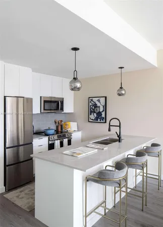 a kitchen with stainless steel appliances granite countertop a dining table chairs refrigerator and sink