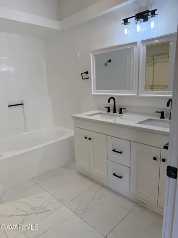 a bathroom with a bathtub sink vanity and mirror
