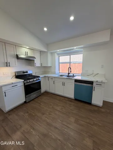 a kitchen with stainless steel appliances a sink window and cabinets
