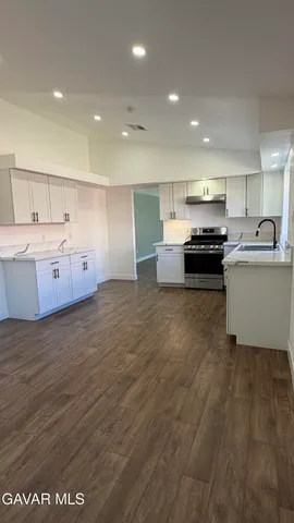 a large kitchen with stainless steel appliances a large counter top a stove a sink and a refrigerator