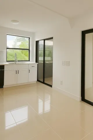 a view of an empty room with window and a kitchen