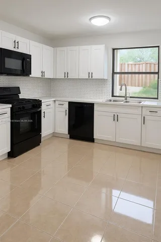 a kitchen with granite countertop white cabinets and black stainless steel appliances