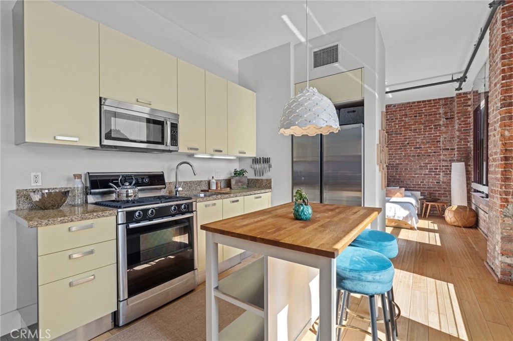 460 South Spring Street, Unit 302 Los Angeles, CA 90013 - Photo 11 of 24 a kitchen with stainless steel appliances granite countertop a stove a sink dishwasher and white cabinets with wooden floor