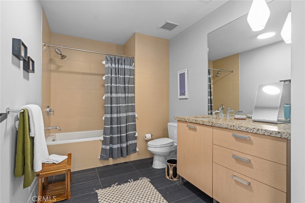460 South Spring Street, Unit 302 Los Angeles, CA 90013 - Photo 15 of 24 a bathroom with a granite countertop sink a toilet a mirror and shower