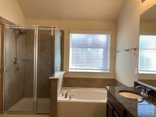 a bathroom with a granite countertop tub shower and sink