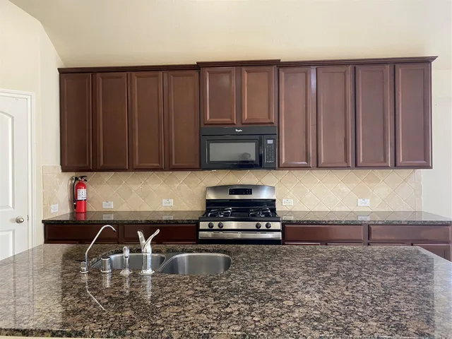 a kitchen with wooden cabinets a microwave and a sink
