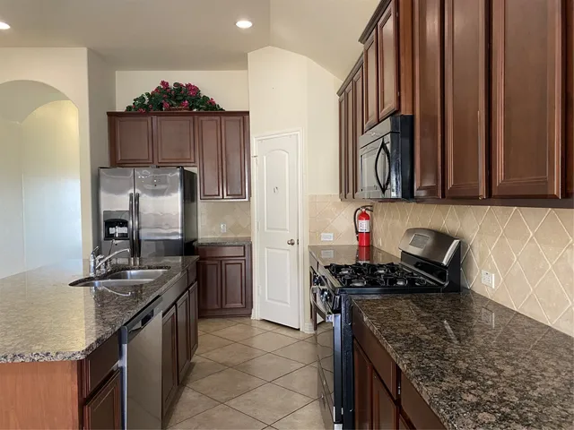 a kitchen with stainless steel appliances granite countertop a sink stove and refrigerator