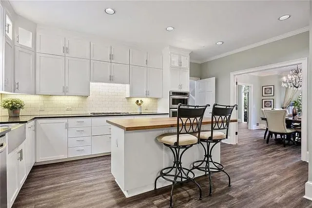 a kitchen with stainless steel appliances granite countertop white cabinets and wooden floor