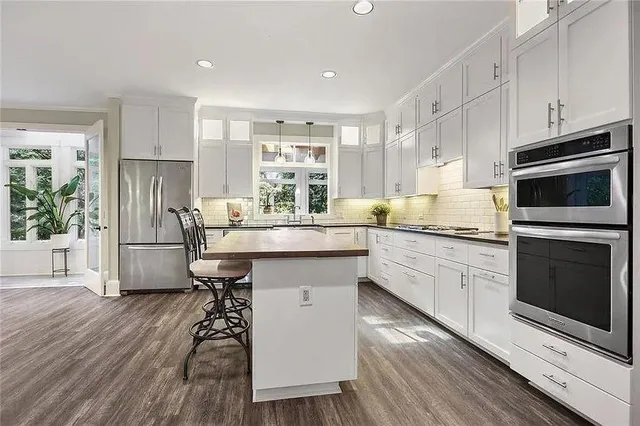 a kitchen with stainless steel appliances a microwave a stove a sink dishwasher a refrigerator and cabinets with wooden floor