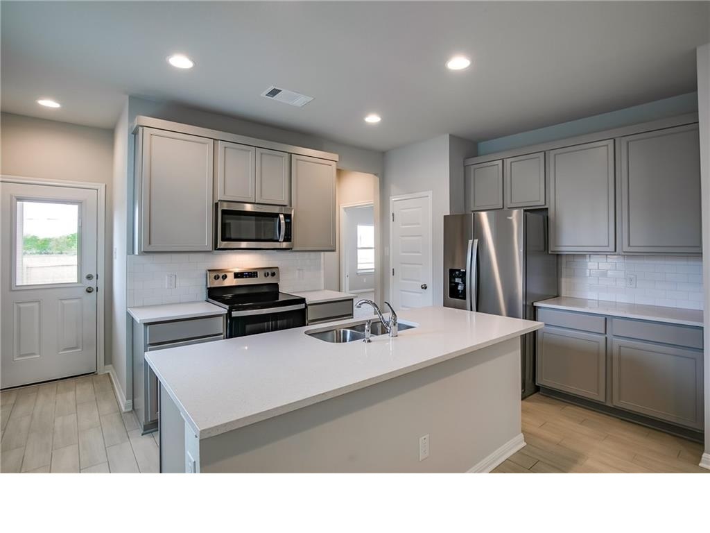 237 Unforgiven Lane Jarrell, TX 76537 - Photo 7 of 20 a kitchen with refrigerator cabinets and wooden floor