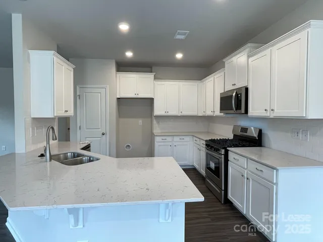 a kitchen with kitchen island white cabinets sink and stainless steel appliances