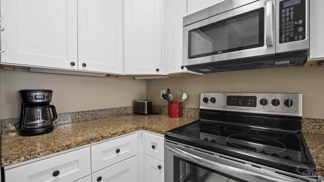 a kitchen with granite countertop white cabinets and stainless steel appliances