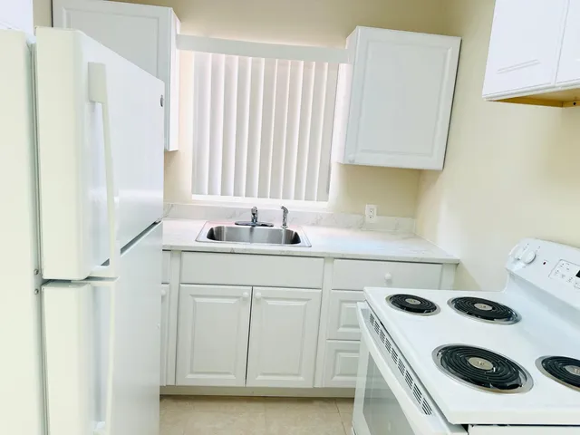 a kitchen with a white stove top oven sink and cabinets