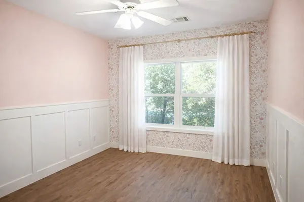 an empty room with wooden floor fan and windows