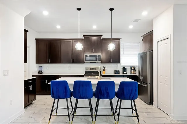 a large kitchen with cabinets chairs stainless steel appliances and a counter space