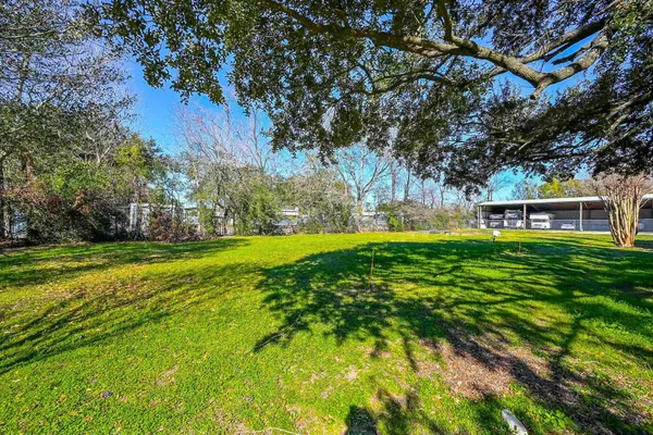 a view of a house with a big yard and large trees