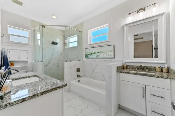 a bathroom with a granite countertop sink mirror and a bath tub
