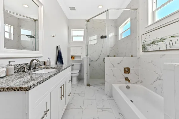a bathroom with a granite countertop sink a toilet and bathtub